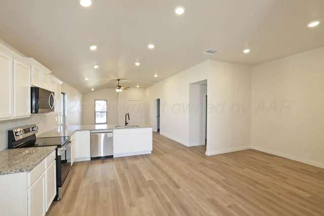 a large kitchen with stainless steel appliances a large counter top a stove a sink and a refrigerator