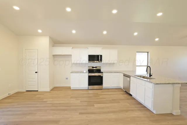 a large kitchen with stainless steel appliances granite countertop a stove and a refrigerator