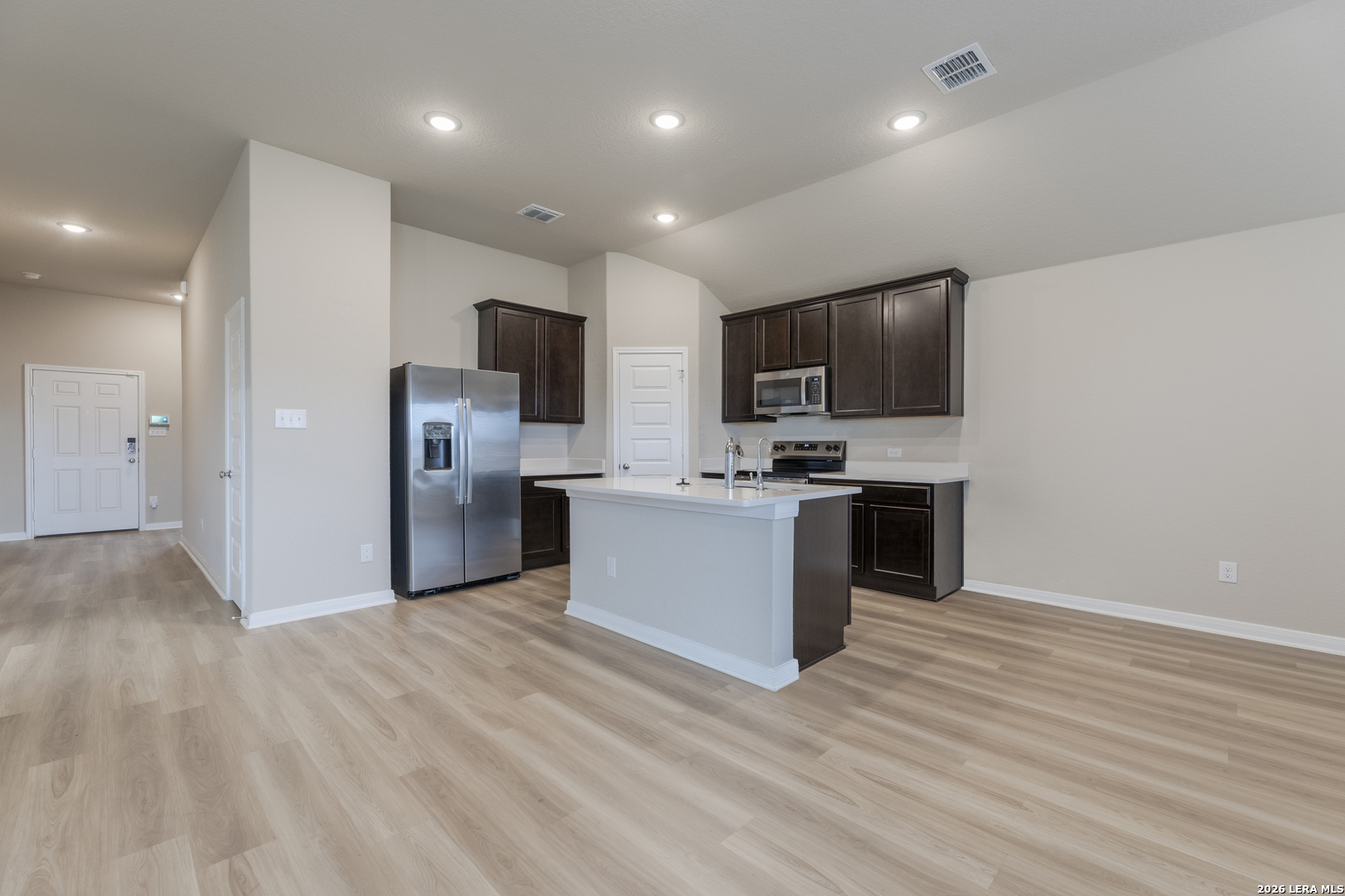 3035 Selhurst Street Converse, TX 78109 - Photo 6 of 18 a large kitchen with stainless steel appliances kitchen island a stove a refrigerator a sink a microwave oven with cabinets and wooden floor