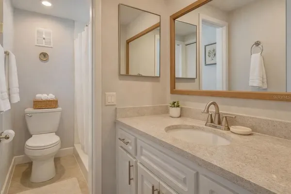 a bathroom with a granite countertop sink a toilet and a mirror