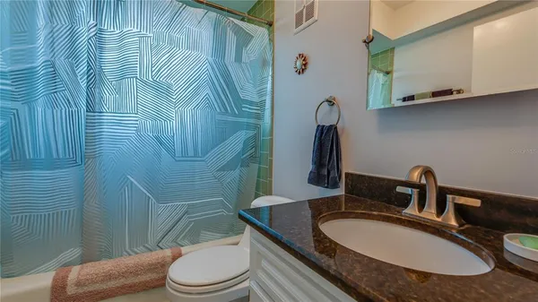 a bathroom with a granite countertop toilet sink and mirror