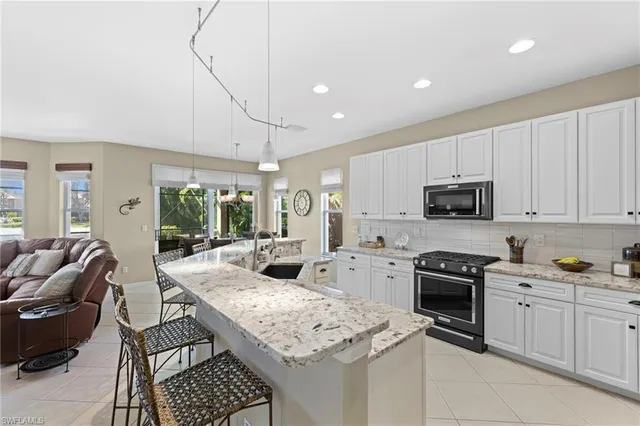 a kitchen with stainless steel appliances granite countertop a stove top oven a sink dishwasher and white cabinets with wooden floor
