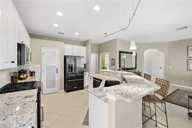 a kitchen with stainless steel appliances kitchen island granite countertop a refrigerator and a stove top oven