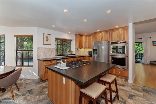 a kitchen with stainless steel appliances granite countertop a stove a refrigerator a kitchen island a table and chairs
