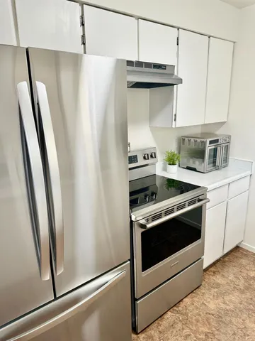 a kitchen with stainless steel appliances a refrigerator a sink and white cabinets