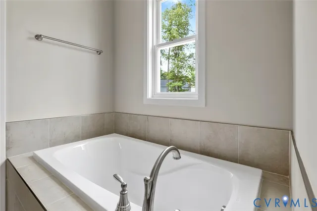 a white bath tub sitting in a bathroom next to a window