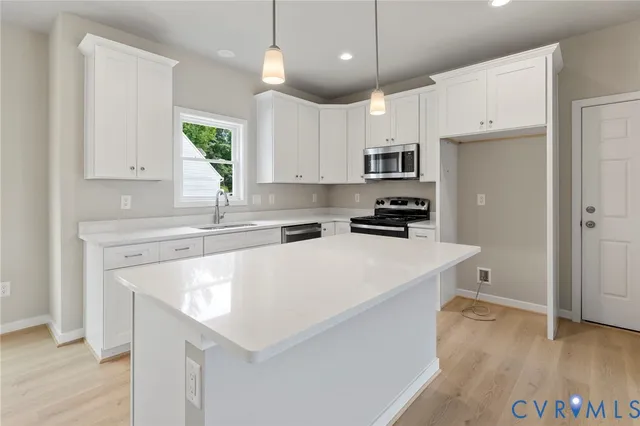 a kitchen with stainless steel appliances granite countertop a sink a stove a refrigerator and white cabinets