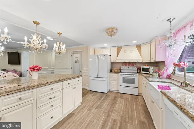 a kitchen with granite countertop a white cabinets and chandelier
