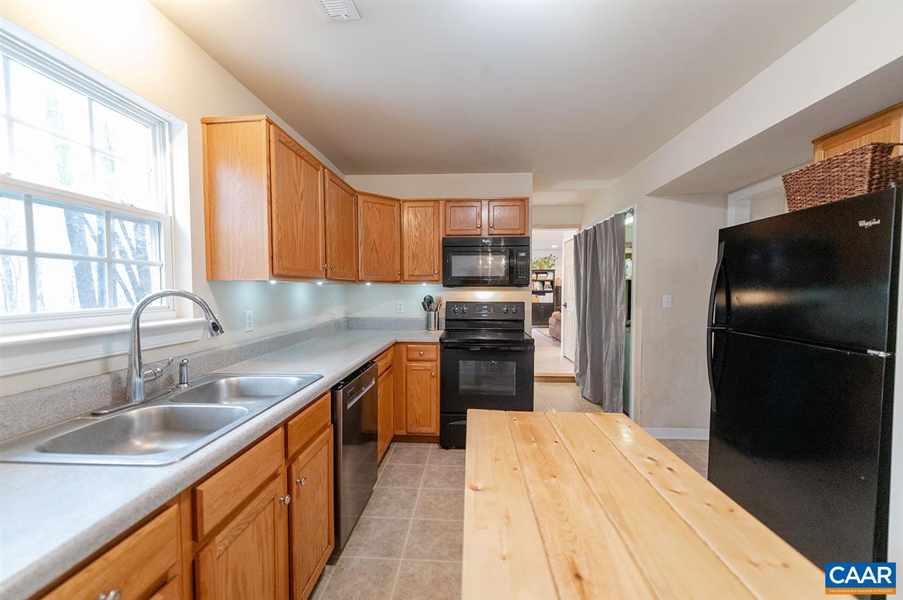 3683 Irish Road Esmont, VA 22937 - Photo 13 of 42 a kitchen with stainless steel appliances a refrigerator sink and wooden cabinets