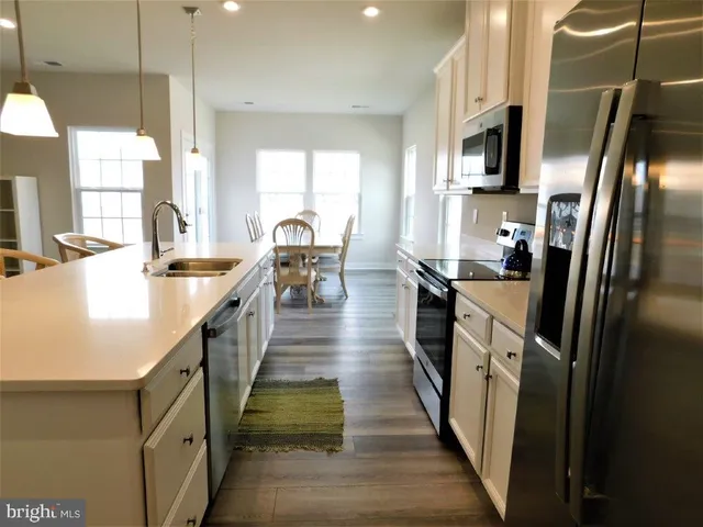 a kitchen with stainless steel appliances a refrigerator a stove a sink a dining table and chairs