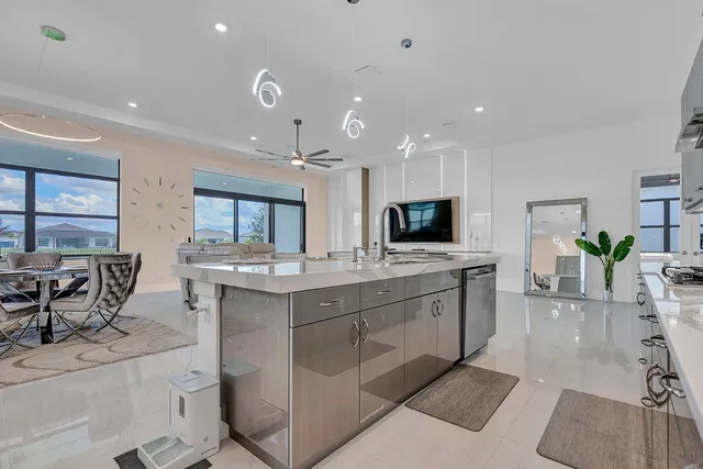 a large white kitchen with a large window and chairs