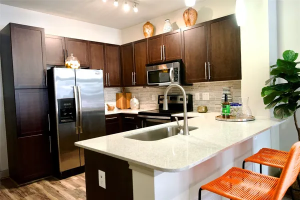 a kitchen with stainless steel appliances wooden cabinets a refrigerator and a sink