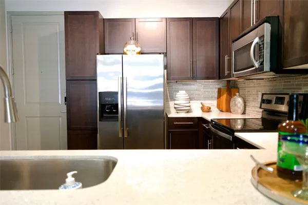 a kitchen with stainless steel appliances kitchen island granite countertop a refrigerator a stove and a sink with wooden floor