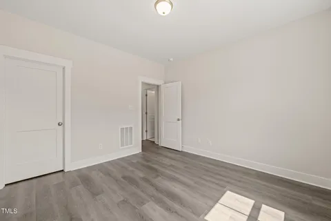a view of an empty room with wooden floor and windows