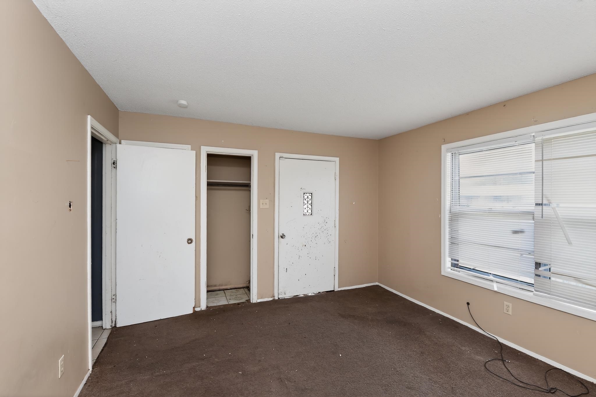 645 Parkrose Road Memphis, TN 38109 - Photo 17 of 32 Carpeted room with neutral-toned walls, a double window featuring horizontal blinds, and multiple access points