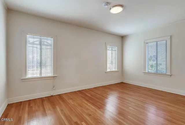 a view of an empty room with wooden floor and a window