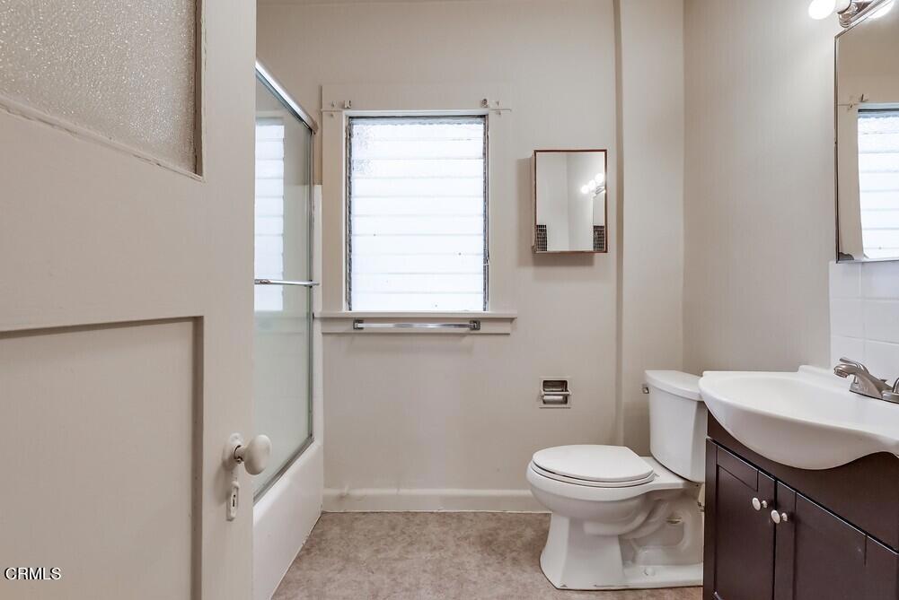 833-835 North Ridgewood Place Los Angeles, CA 90038 - Photo 19 of 28 a bathroom with a toilet a sink a window and mirror