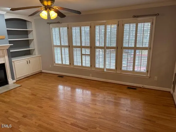 a view of an empty room with a window and wooden floor