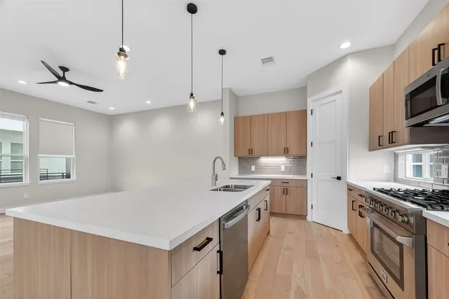 a kitchen with stainless steel appliances granite countertop a sink a stove and a refrigerator