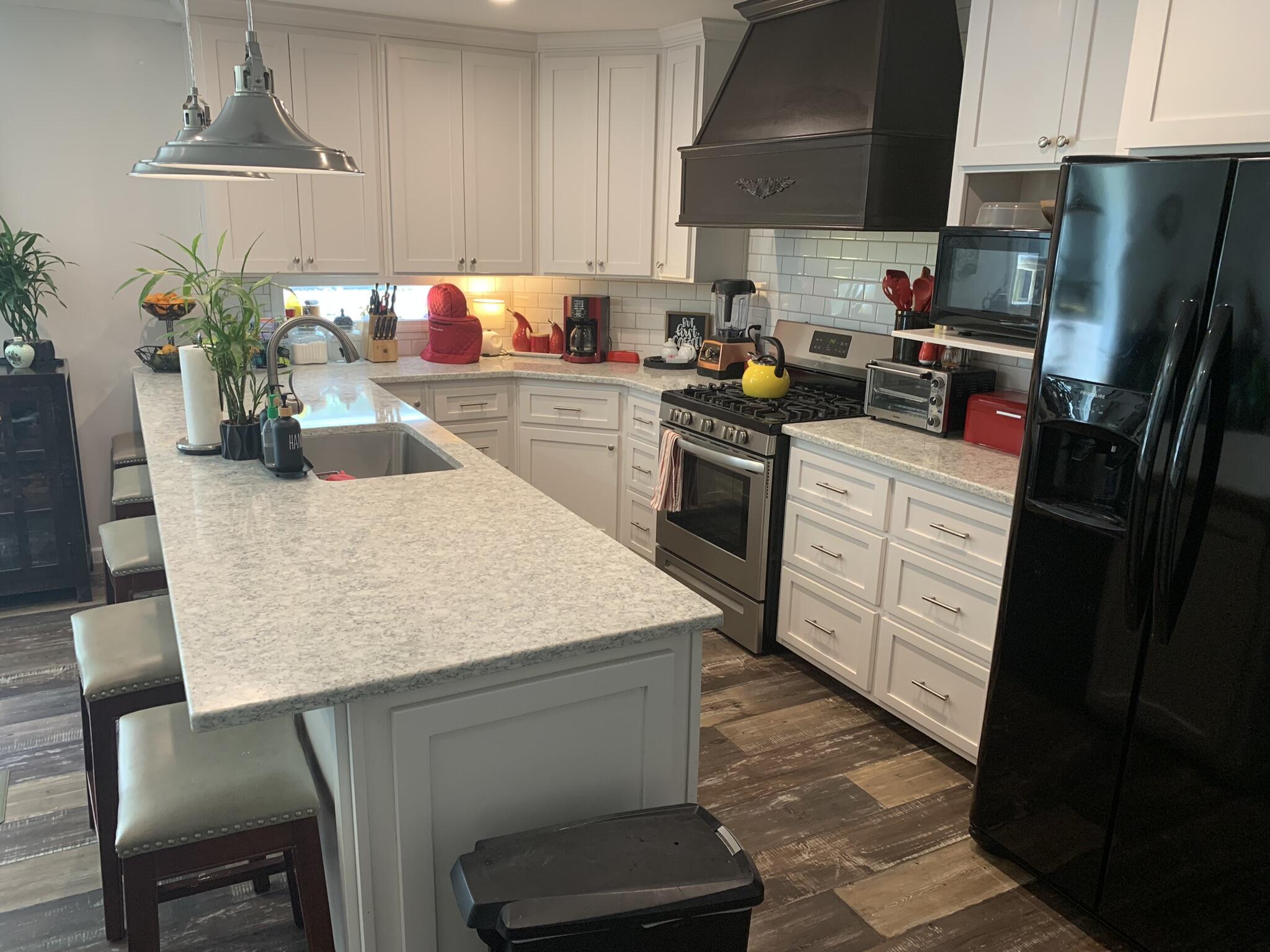 6196 Lake Ella Road Crestview, FL 32539 - Photo 8 of 29 a kitchen with stainless steel appliances a sink a table a refrigerator a stove a microwave a dining table and chairs