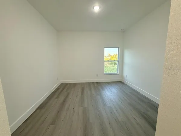 an empty room with wooden floor and window