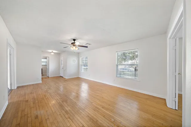 a view of an empty room with wooden floor and a window