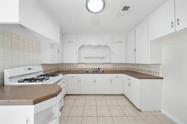 a kitchen with granite countertop a sink a stove and cabinets