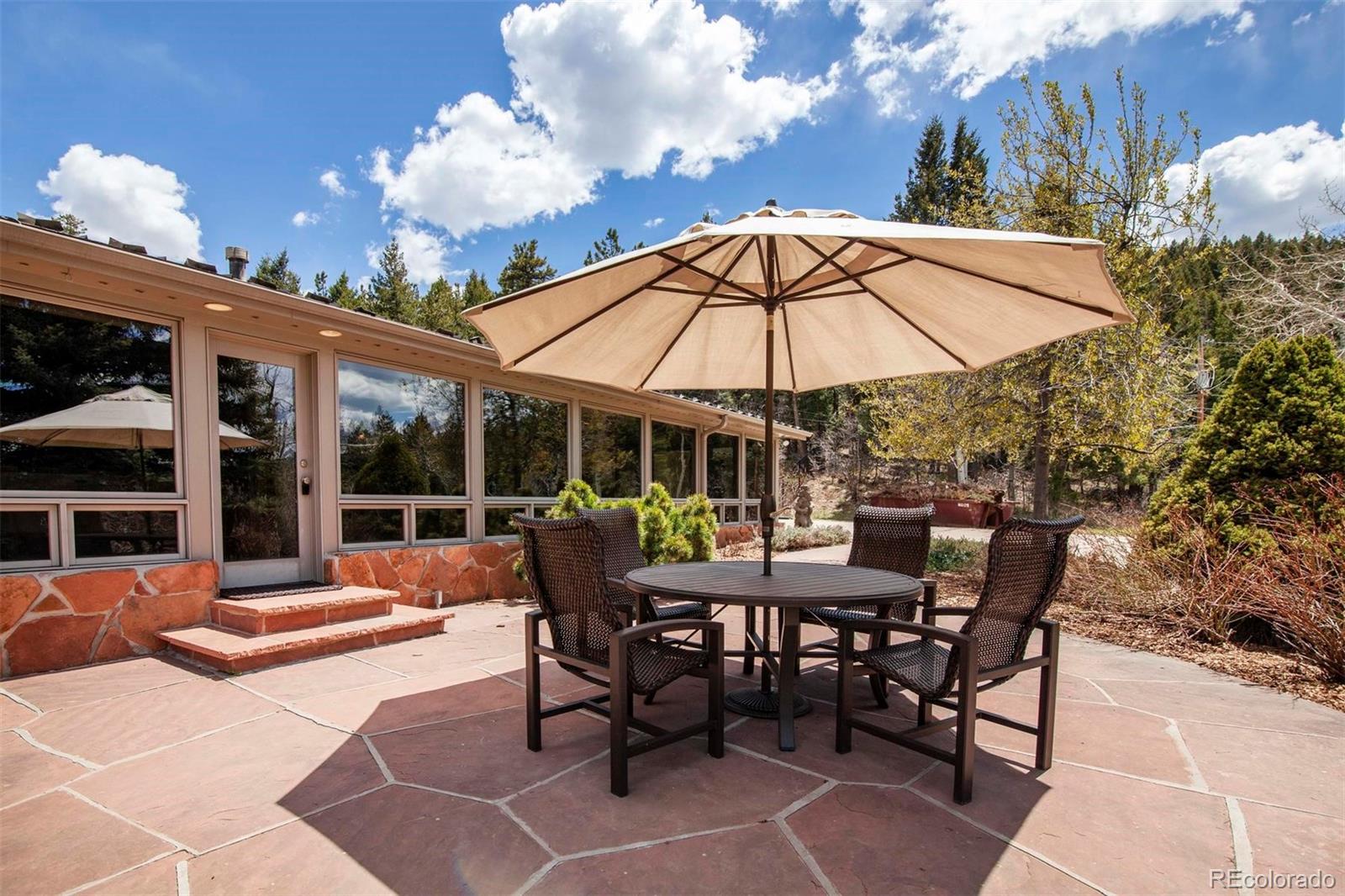 18332 Stone Gate Drive Morrison, CO 80465 - Photo 4 of 40 a view of a patio with a dining table and chairs under an umbrella