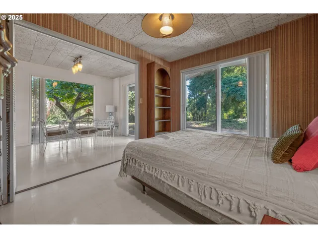 a bedroom with a bed and large windows