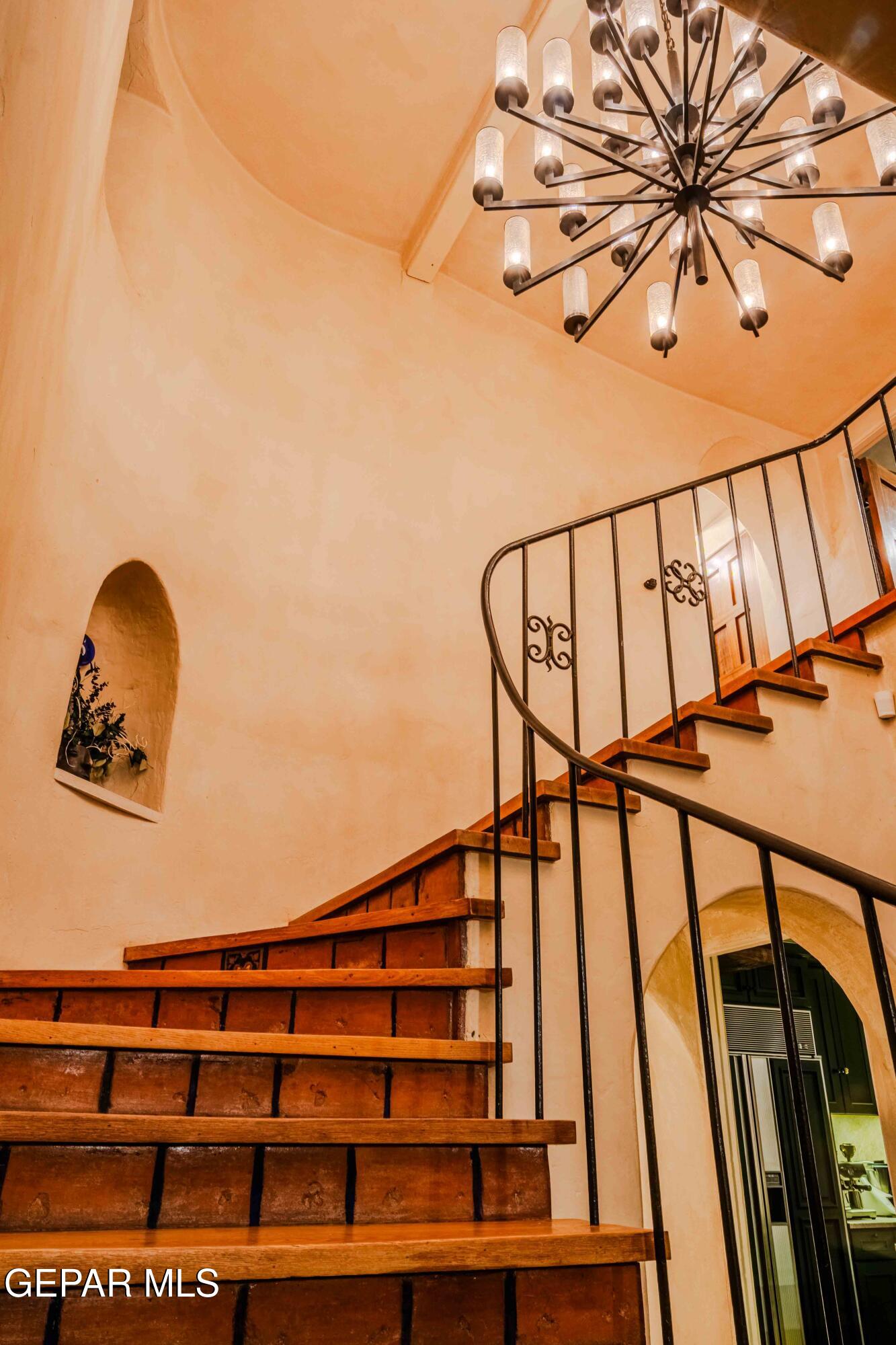701 Rim Road El Paso, TX 79968 - Photo 29 of 54 a view of staircase with wooden floor and a chandelier