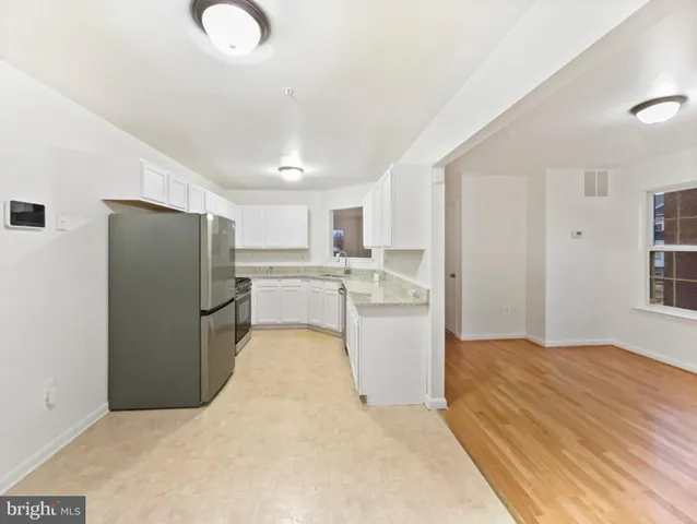 a kitchen with refrigerator and white cabinets