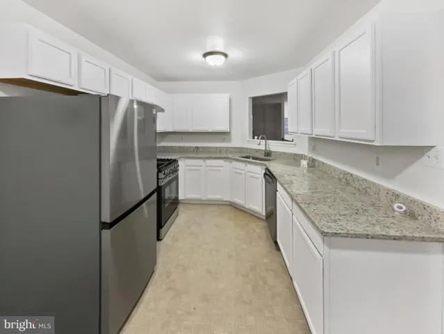 a kitchen with stainless steel appliances granite countertop a refrigerator a sink a stove and oven