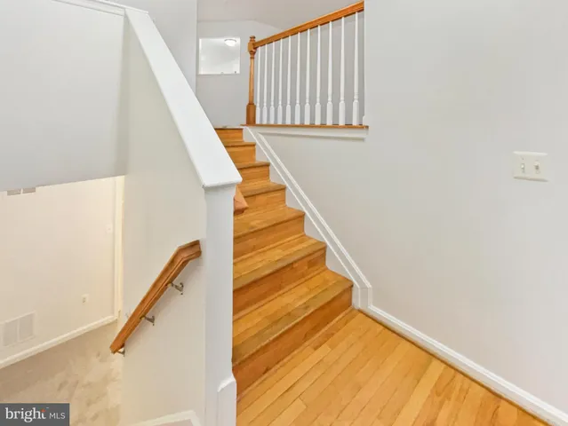 a view of staircase with wooden floor and white walls