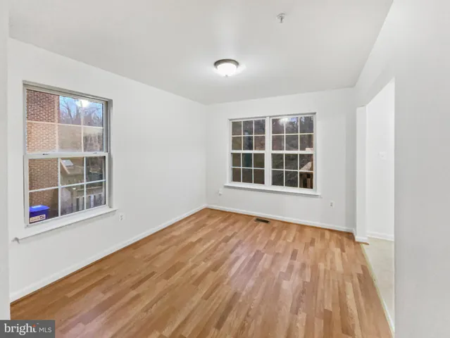 a view of an empty room with wooden floor and windows
