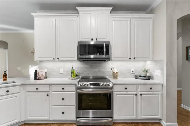 a kitchen with white cabinets and appliances