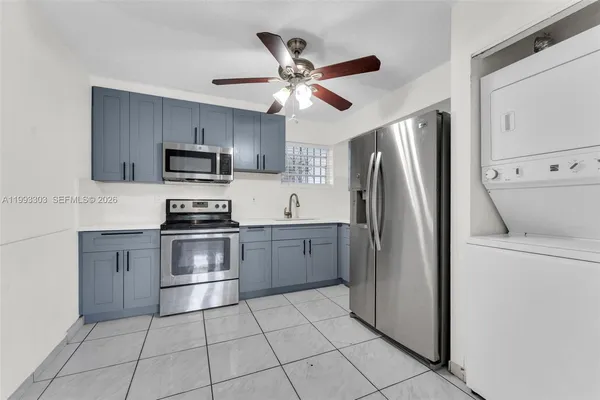 a kitchen with a refrigerator a sink and white cabinets