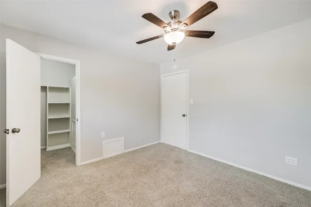 an empty room with closet and a ceiling fan
