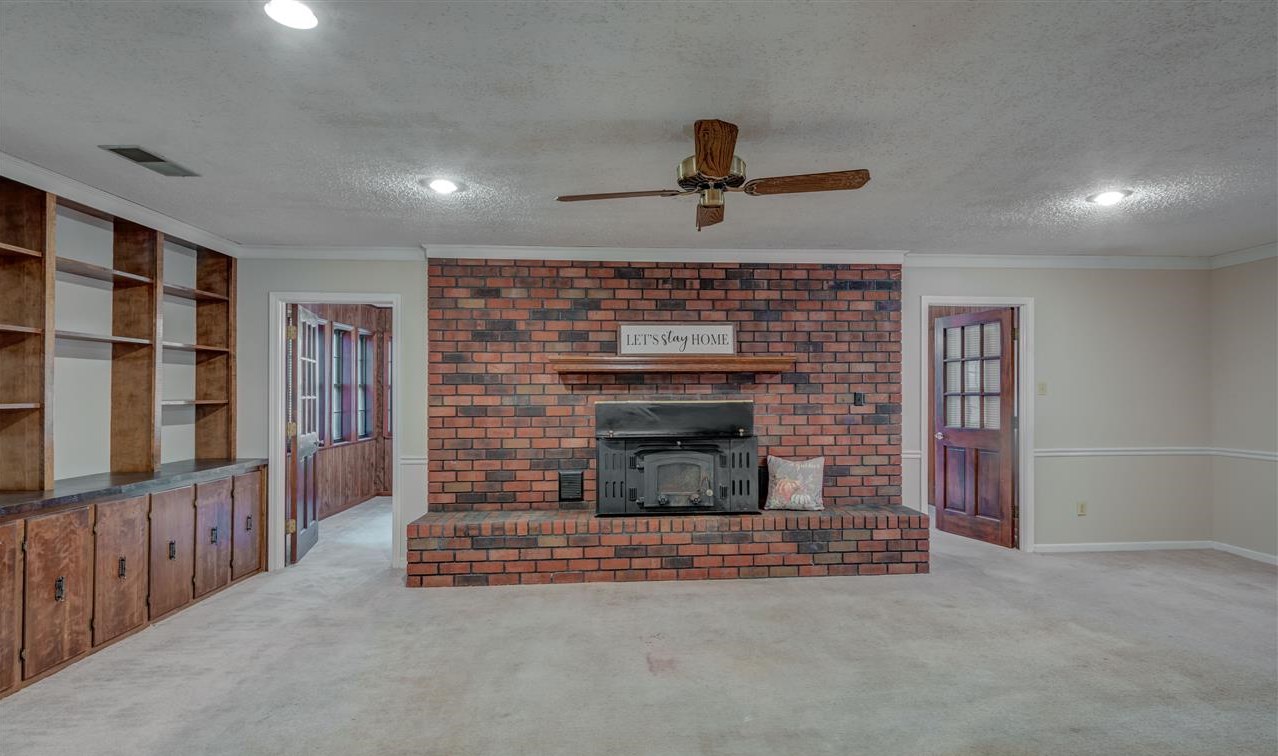 Cozy den with wood burning fireplace. Nice shelving for family photos, books, or whatever you want to display.