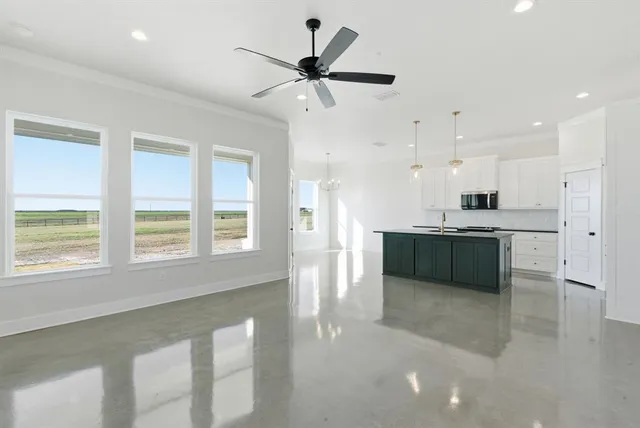 a large kitchen with stainless steel appliances kitchen island granite countertop a refrigerator a sink a stove and white cabinets with wooden floor