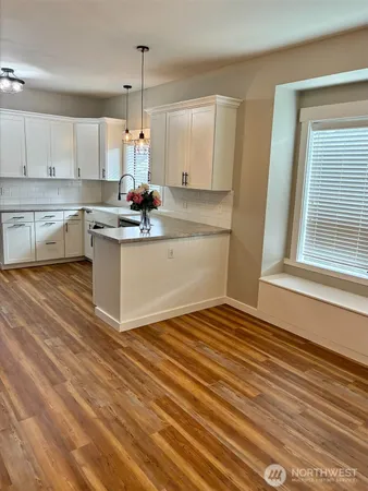 a kitchen with kitchen island granite countertop a sink cabinets and wooden floor