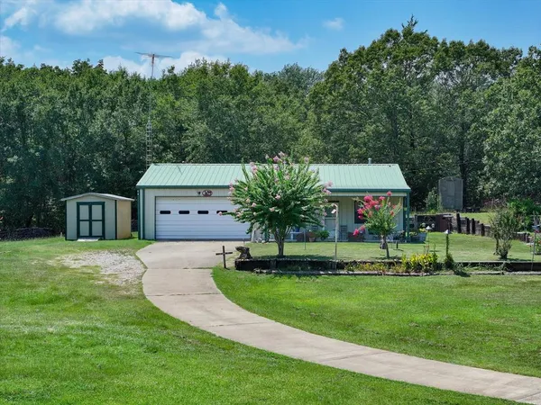 a front view of a house with a garden and trees