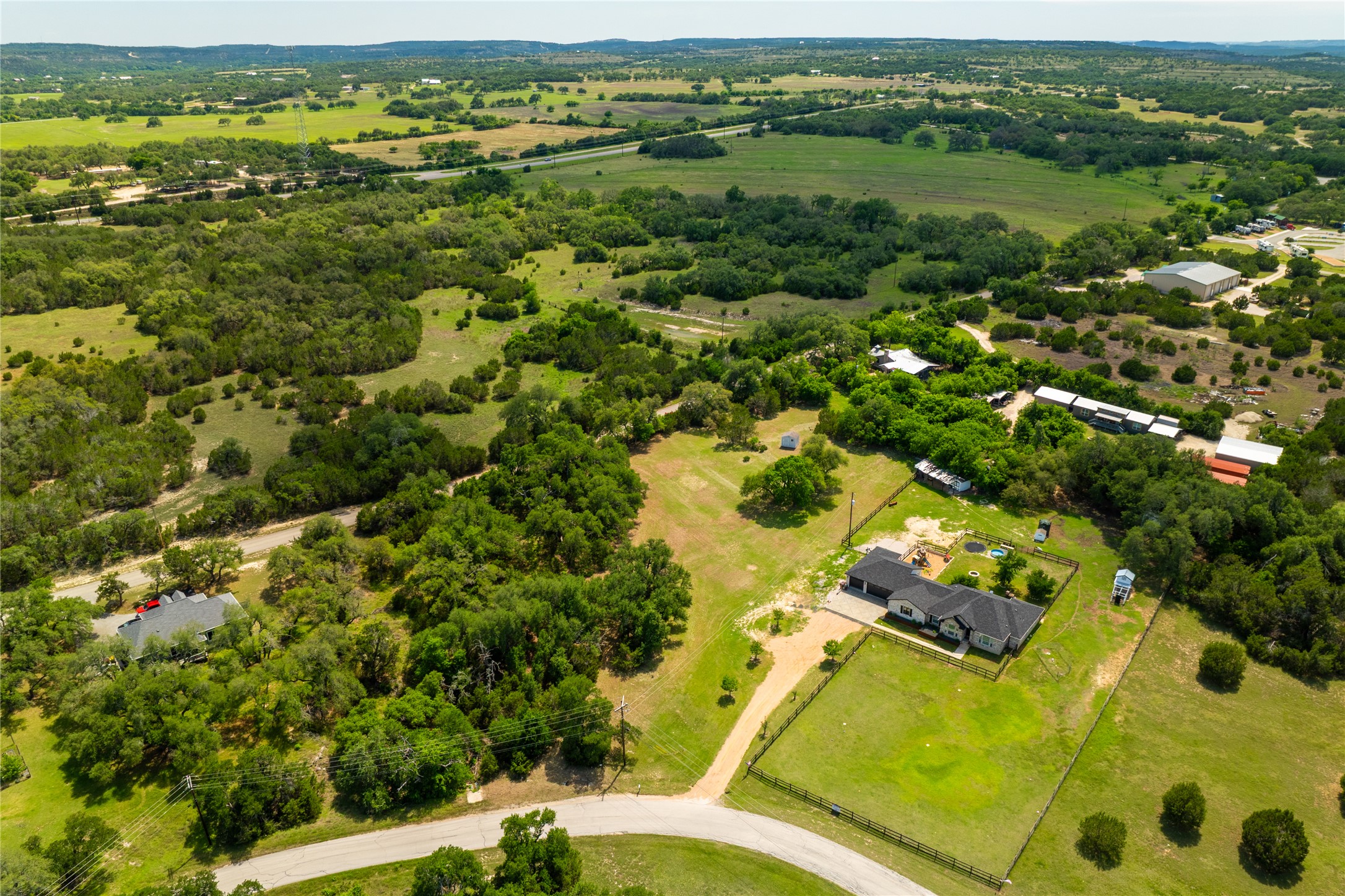 187 Beauchamp Road Dripping Springs, TX 78620 - Photo 16 of 19 Expansive aerial showcasing a single-story residence with an attached garage, a verdant lawn, and a perimeter fence