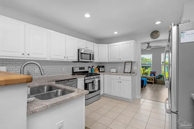 a kitchen with kitchen island granite countertop white cabinets white appliances a sink and a window