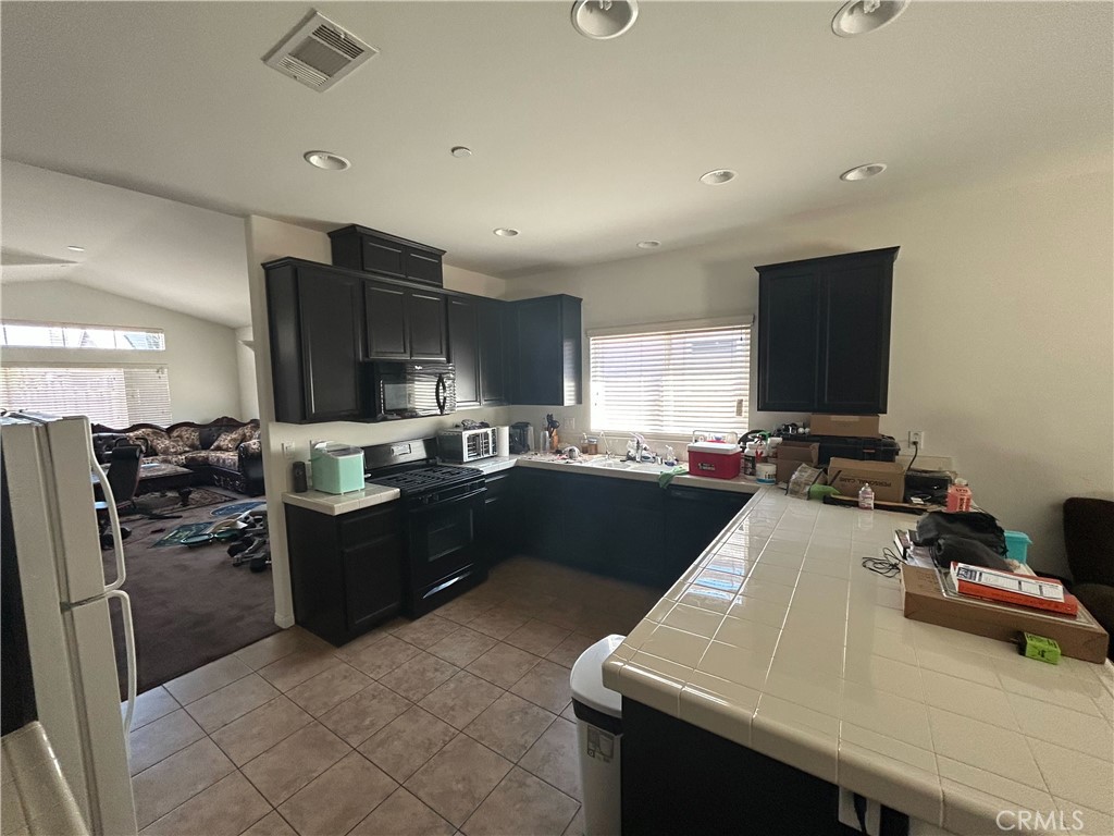 772 St Alban Road San Jacinto, CA 92583 - Photo 9 of 25 a kitchen with a refrigerator a stove top oven a sink dishwasher and wooden cabinets with wooden floor