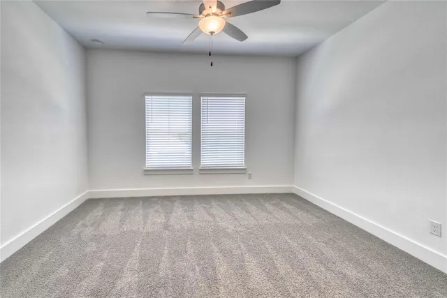 an empty room with a window and a ceiling fan