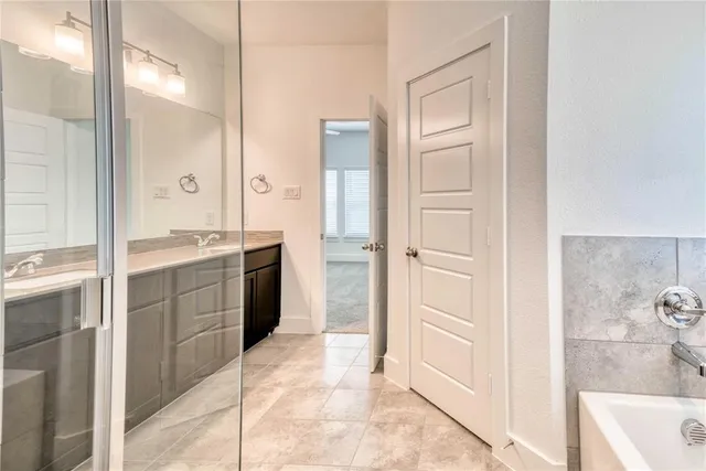 a bathroom with a granite countertop sink mirror and a bathtub