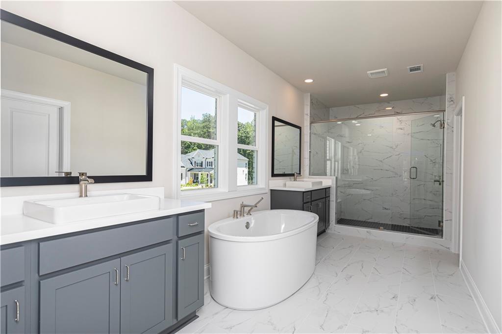 2475 Stewart Road Cumming, GA 30041 - Photo 20 of 30 a bathroom with a double vanity sink a mirror and a bathtub