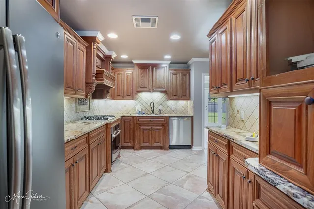 a large kitchen with granite countertop a large stove top oven refrigerator and cabinets