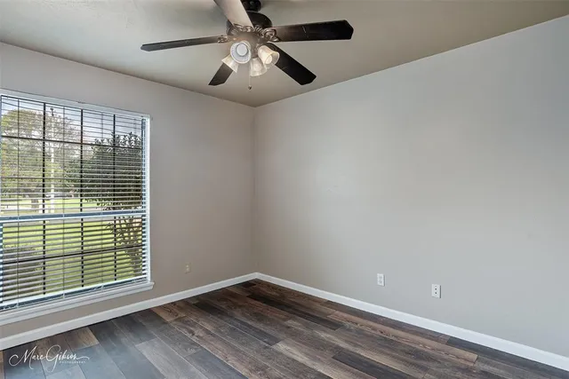 an empty room with windows and fan