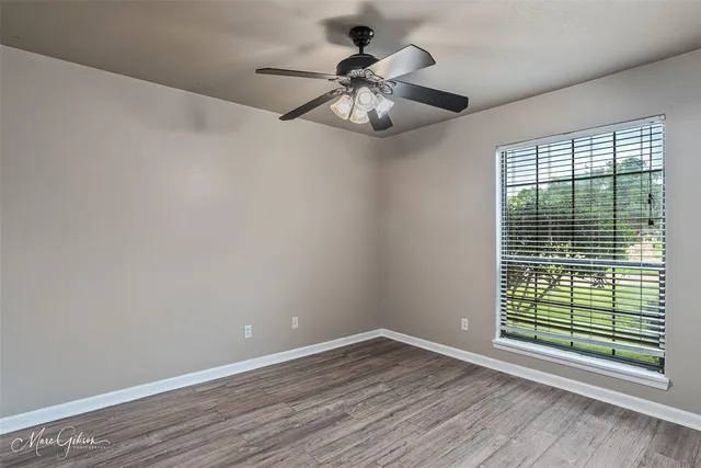 a view of an empty room with wooden floor and a window